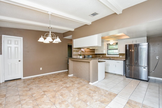 kitchen featuring light tile patterned floors, kitchen peninsula, beamed ceiling, stainless steel fridge, and decorative light fixtures