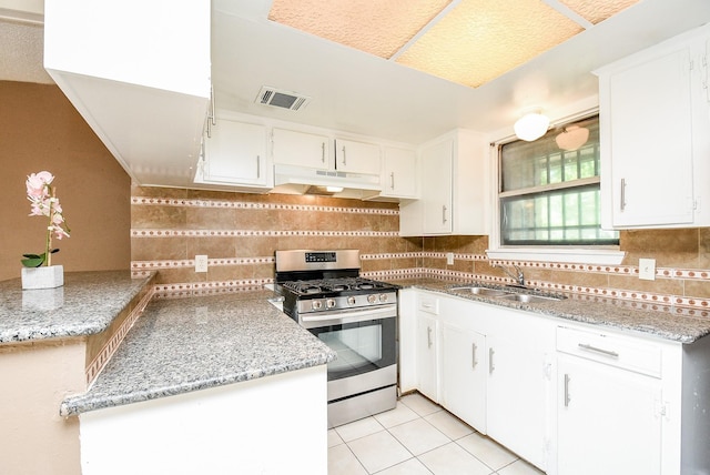 kitchen featuring under cabinet range hood, stainless steel gas range, white cabinets, and a sink