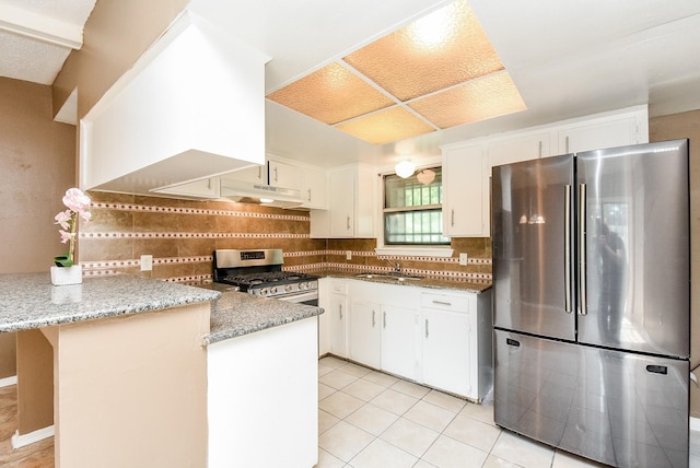 kitchen with kitchen peninsula, appliances with stainless steel finishes, tasteful backsplash, and light stone countertops