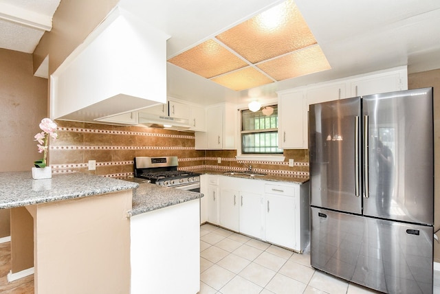 kitchen featuring stainless steel appliances, white cabinets, a peninsula, and decorative backsplash