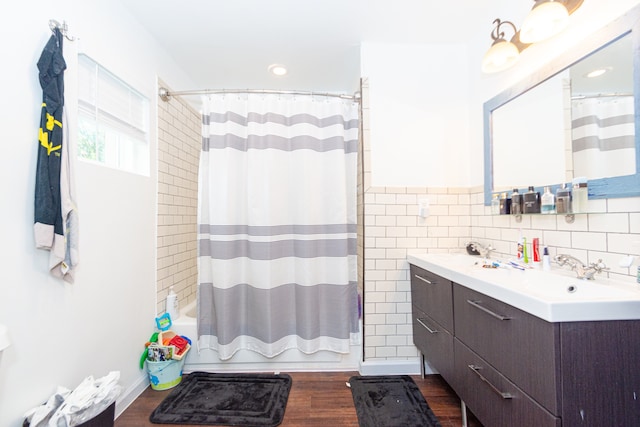 bathroom with tasteful backsplash, shower / bath combination with curtain, tile walls, vanity, and hardwood / wood-style flooring