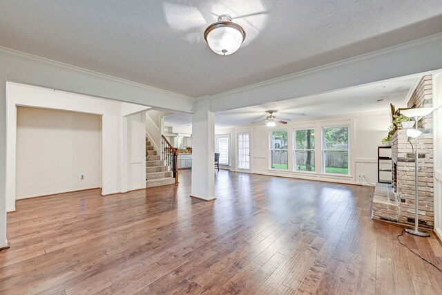 unfurnished living room with ceiling fan, wood-type flooring, and ornamental molding