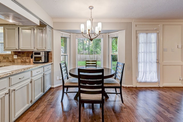 dining room with ornamental molding, a textured ceiling, dark hardwood / wood-style floors, and an inviting chandelier