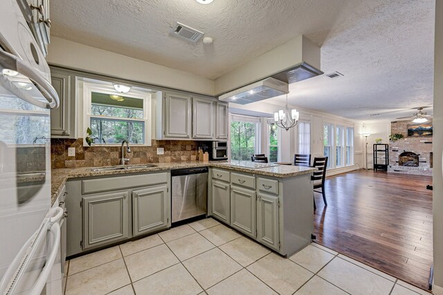 kitchen featuring appliances with stainless steel finishes, kitchen peninsula, ceiling fan with notable chandelier, and plenty of natural light