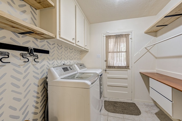 laundry area featuring light tile patterned flooring, cabinets, a textured ceiling, and separate washer and dryer