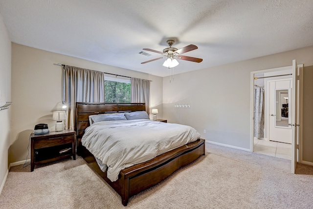 carpeted bedroom with a textured ceiling, ceiling fan, and ensuite bathroom