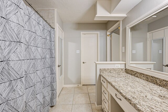 bathroom with vanity, a textured ceiling, and tile patterned flooring