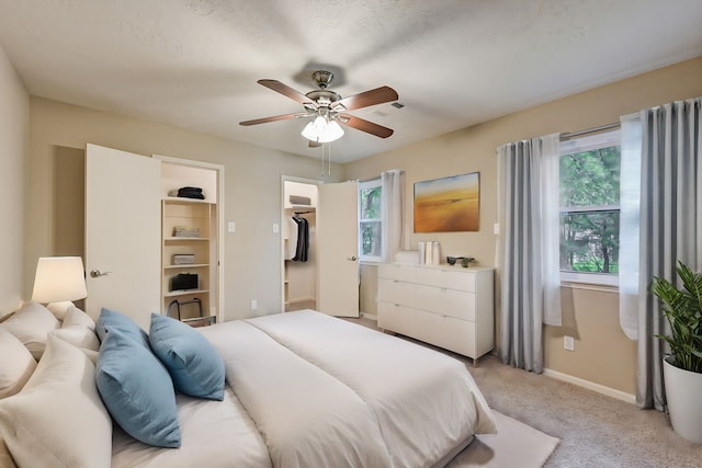 bedroom with ceiling fan, a spacious closet, light carpet, and a closet