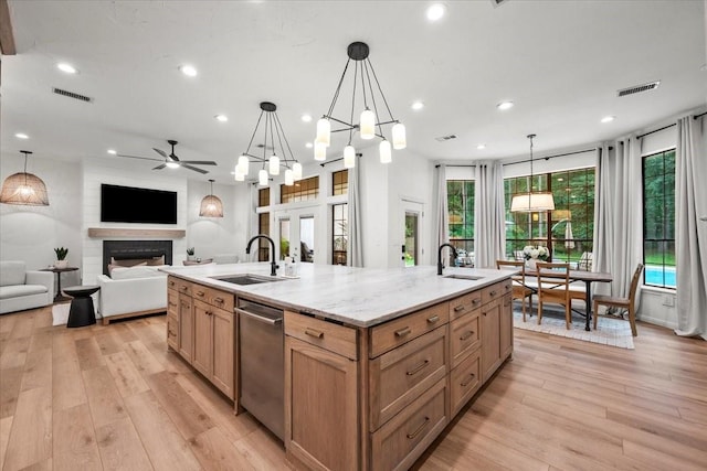 9819 Crestwater Cir, Magnolia, TX 77354 - kitchen featuring a sink, stainless steel dishwasher, a fireplace, an island with sink, and recessed lighting