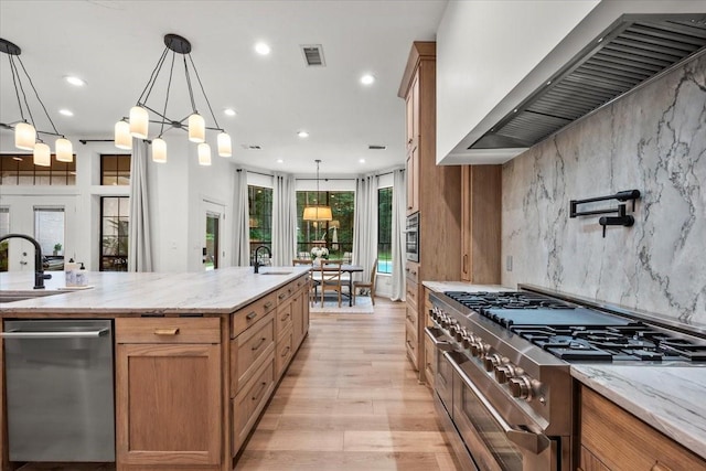 9819 Crestwater Cir, Magnolia, TX 77354 - kitchen featuring wall chimney range hood, stainless steel appliances, recessed lighting, light wood-style floors, and hanging light fixtures