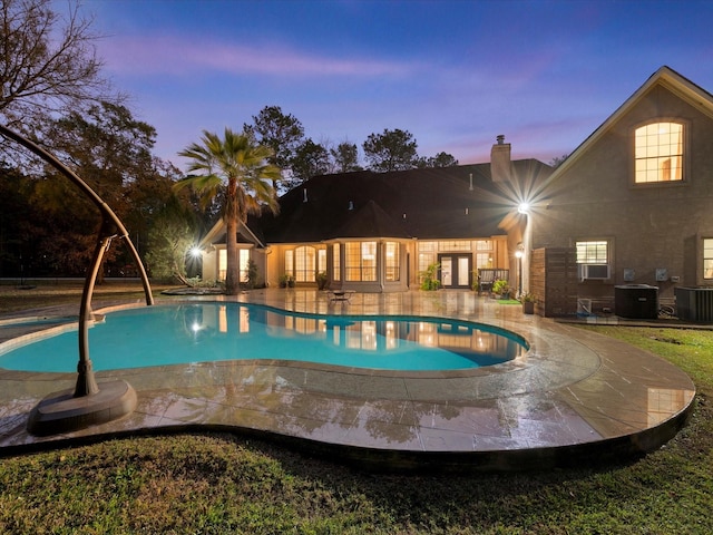 pool at dusk featuring a patio, french doors, and central air condition unit