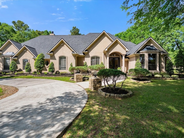 9819 Crestwater Cir, Magnolia, TX 77354 - view of front of home with a front yard, a chimney, stucco siding, and roof with shingles