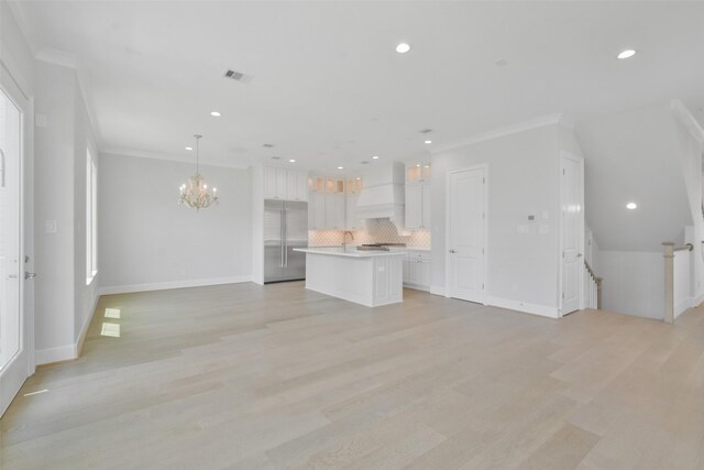 unfurnished living room with a notable chandelier, ornamental molding, and light hardwood / wood-style floors