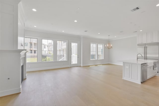 unfurnished living room with a notable chandelier, ornamental molding, and light hardwood / wood-style floors