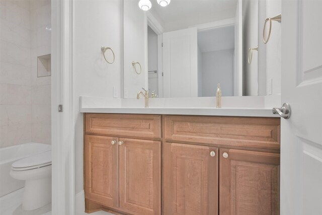 full bathroom featuring vanity, tiled shower / bath, and toilet