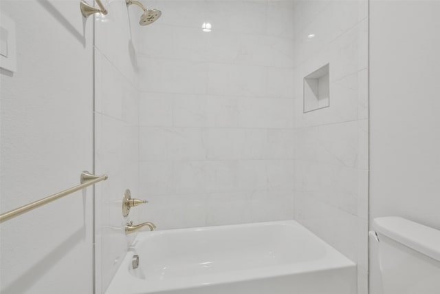 bathroom featuring tiled shower / bath combo and toilet