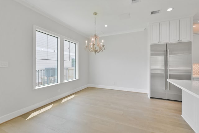 unfurnished dining area featuring light hardwood / wood-style flooring, ornamental molding, and an inviting chandelier