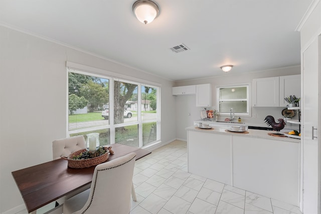 kitchen with white cabinets, sink, kitchen peninsula, light tile patterned floors, and crown molding