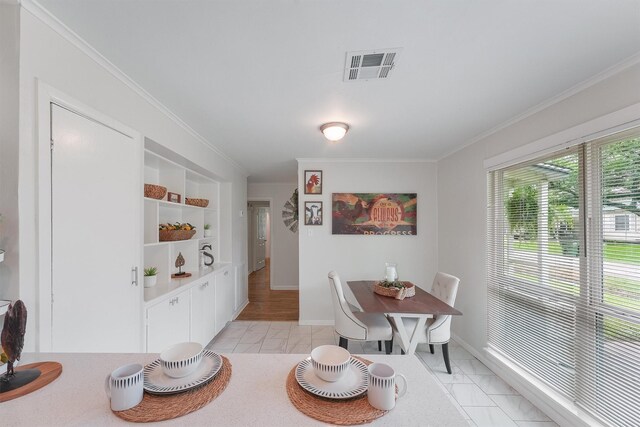 dining space with crown molding and light wood-type flooring