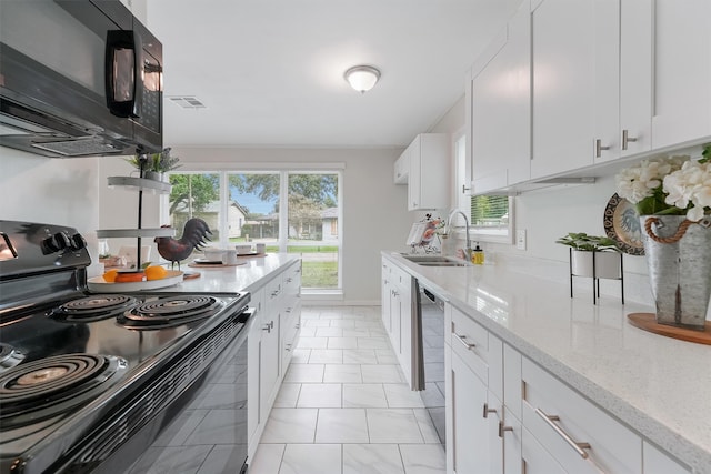 kitchen featuring light tile patterned floors, white cabinets, black appliances, light stone countertops, and sink