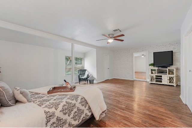 bedroom featuring hardwood / wood-style flooring, brick wall, and ceiling fan