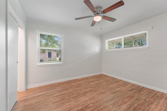 empty room featuring light hardwood / wood-style floors, ornamental molding, a wealth of natural light, and ceiling fan