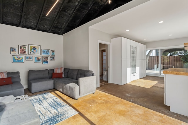 living room featuring lofted ceiling and concrete floors