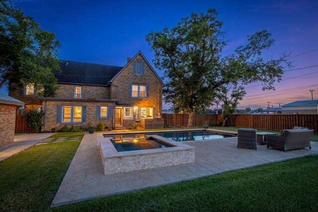 pool at dusk with an in ground hot tub, a yard, an outdoor hangout area, and a patio