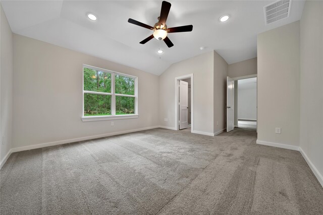 unfurnished bedroom featuring ceiling fan, lofted ceiling, light carpet, and a walk in closet