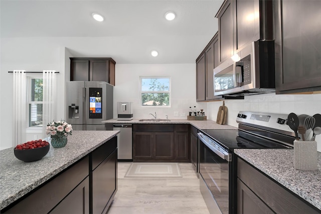 kitchen featuring stainless steel appliances, tasteful backsplash, sink, and light stone counters