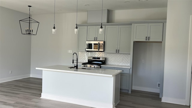 kitchen with decorative light fixtures, a kitchen island with sink, appliances with stainless steel finishes, and tasteful backsplash