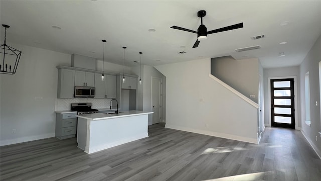 kitchen with light hardwood / wood-style floors, stainless steel appliances, a kitchen island with sink, sink, and gray cabinets