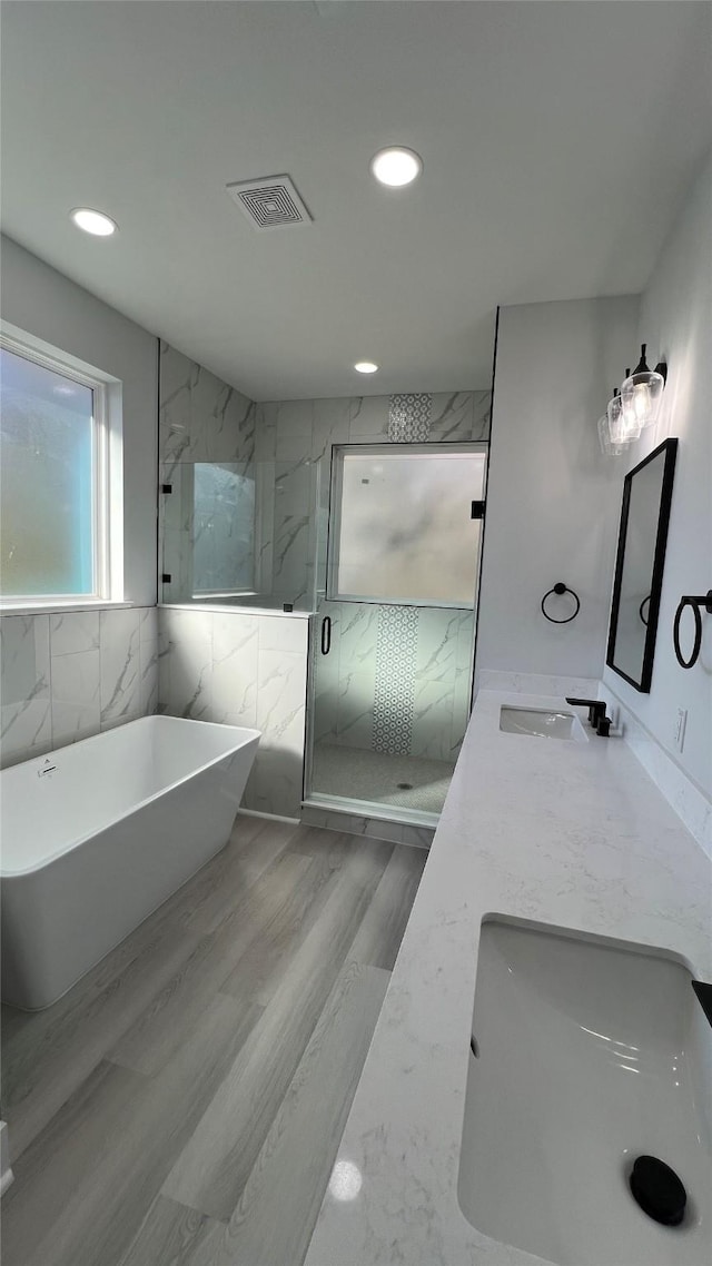 bathroom featuring hardwood / wood-style flooring, vanity, and shower with separate bathtub