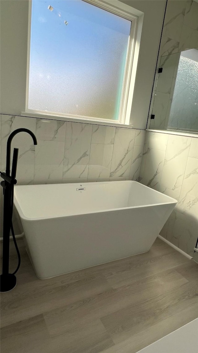 bathroom with a tub, a healthy amount of sunlight, and wood-type flooring