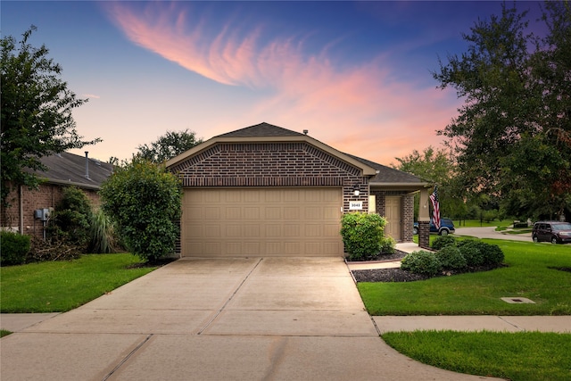 ranch-style home featuring a garage and a lawn