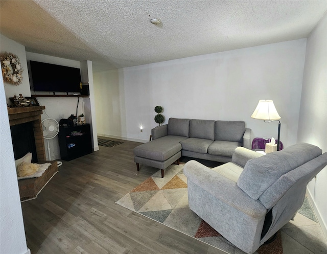 living room with a textured ceiling, a brick fireplace, and hardwood / wood-style floors