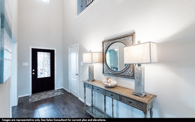 entryway featuring a towering ceiling and dark wood-type flooring