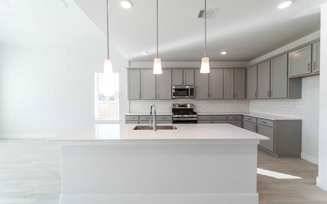 kitchen featuring gray cabinets, visible vents, decorative backsplash, appliances with stainless steel finishes, and a sink