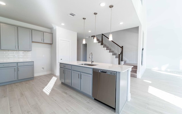 kitchen featuring light countertops, gray cabinetry, wood tiled floor, a sink, and dishwasher