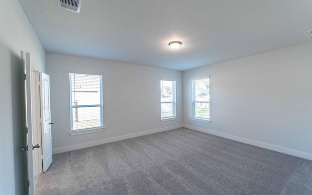 unfurnished room featuring a textured ceiling, carpet flooring, visible vents, and baseboards