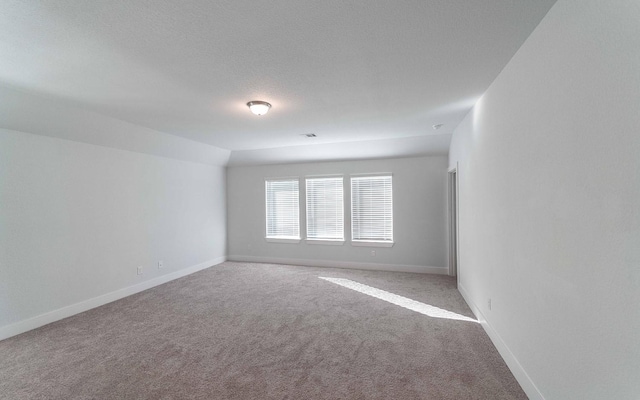 carpeted empty room with a textured ceiling, visible vents, and baseboards