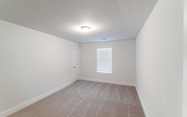 unfurnished room featuring baseboards, a textured ceiling, visible vents, and light colored carpet