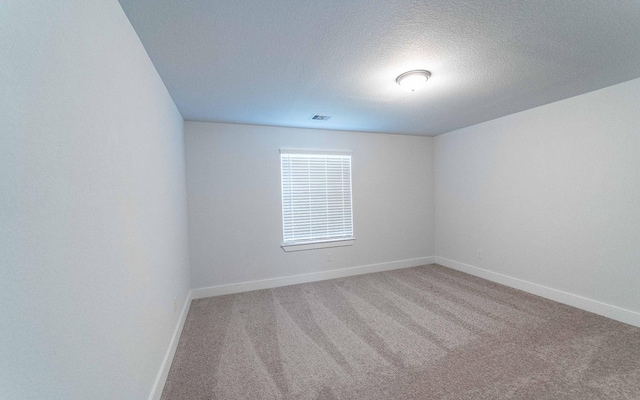 unfurnished room with visible vents, carpet flooring, a textured ceiling, and baseboards