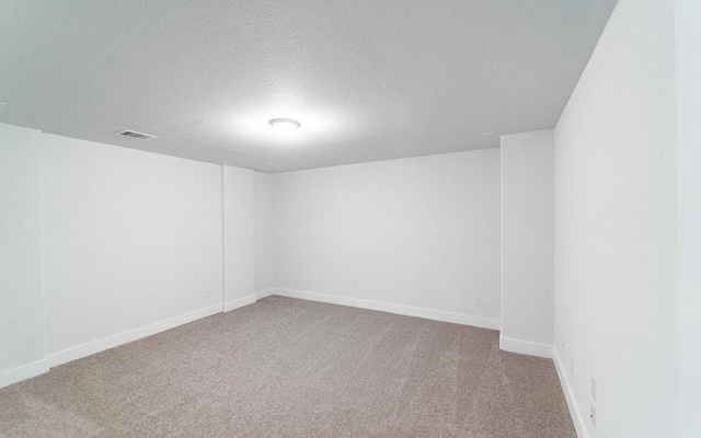 unfurnished room featuring carpet, visible vents, a textured ceiling, and baseboards