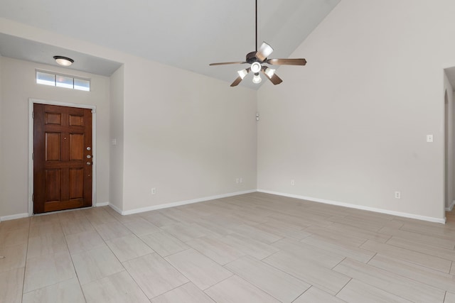 foyer entrance with ceiling fan, vaulted ceiling, and baseboards