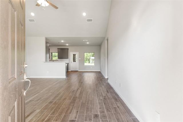 unfurnished living room with a towering ceiling, dark wood-type flooring, and ceiling fan