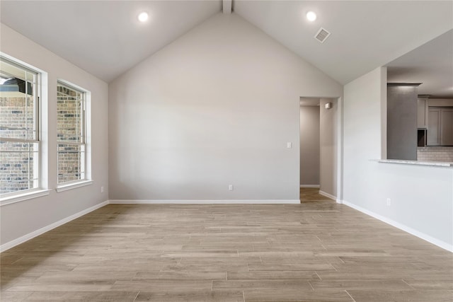 spare room featuring beamed ceiling, light hardwood / wood-style flooring, high vaulted ceiling, and plenty of natural light