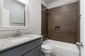 full bathroom with tiled shower / bath combo, vanity, and toilet