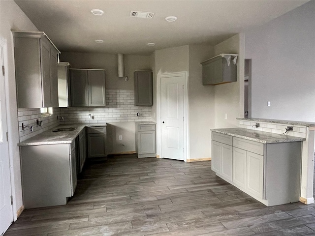 kitchen featuring gray cabinetry, light hardwood / wood-style floors, sink, and tasteful backsplash