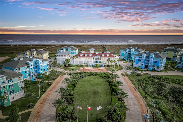 aerial view at dusk featuring a water view and a view of the beach